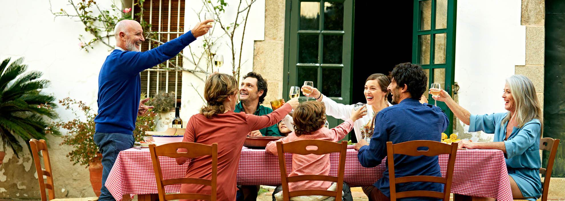 Grandfather giving speech at dinner table with family outisde